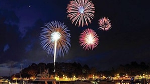A marina at night with boats docked and fireworks in the sky.