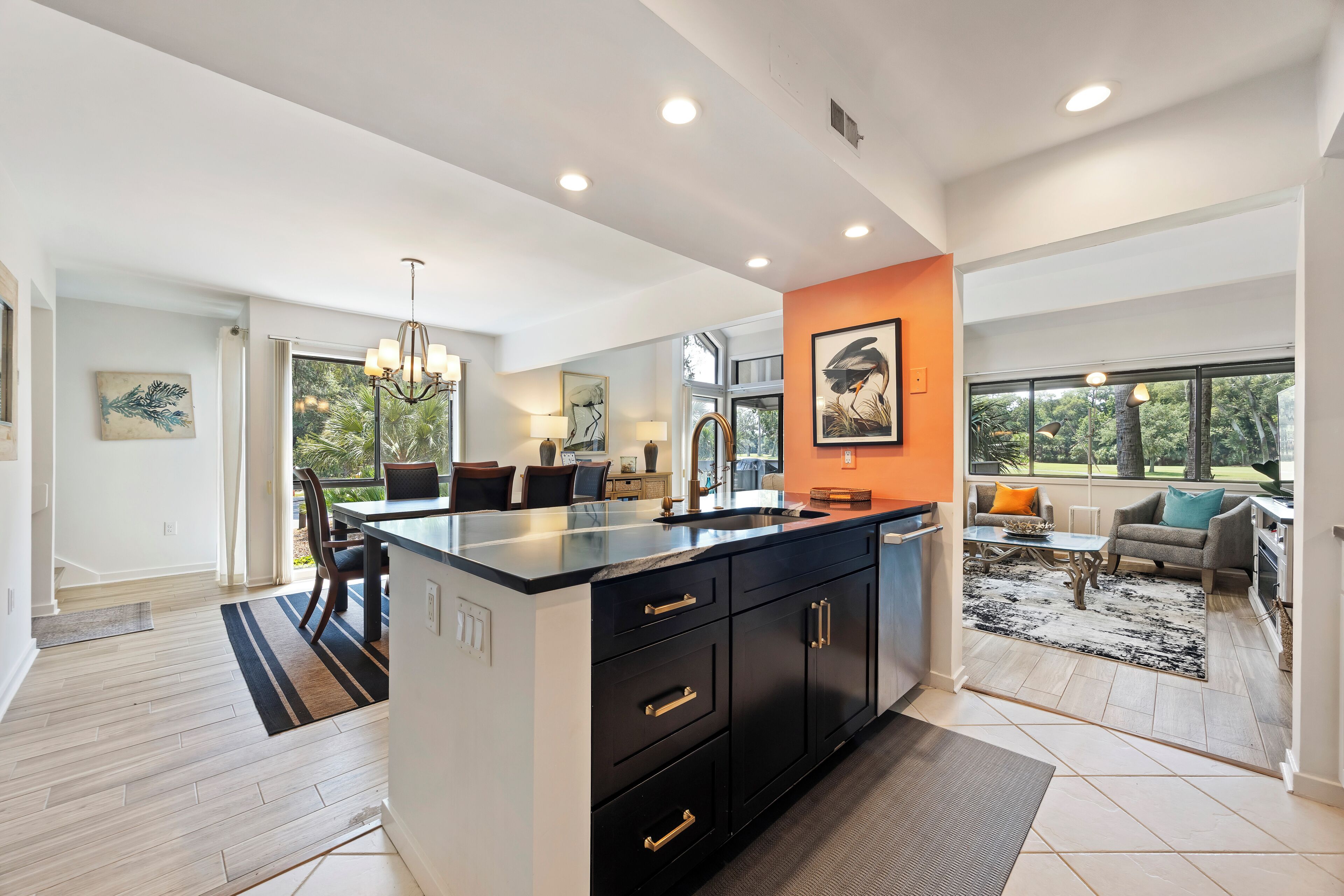 A modern kitchen with a central island, dark cabinetry, and a view to the living area.