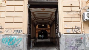 An arched entrance with graffiti on the walls and a person standing in the distance.
