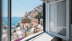 A view from a window overlooking a coastal town with colorful buildings and a prominent church with a dome.
