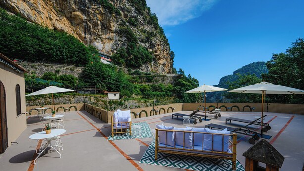 Terraço no telhado com área de estar externa, um pequeno jardim e vista para um penhasco.