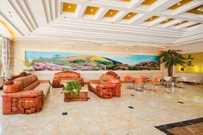 A lobby with leather sofas, a marble floor, and a large landscape painting on the wall.