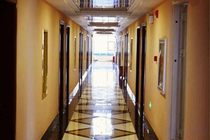 A long, narrow hotel corridor with doors on both sides, leading to rooms.