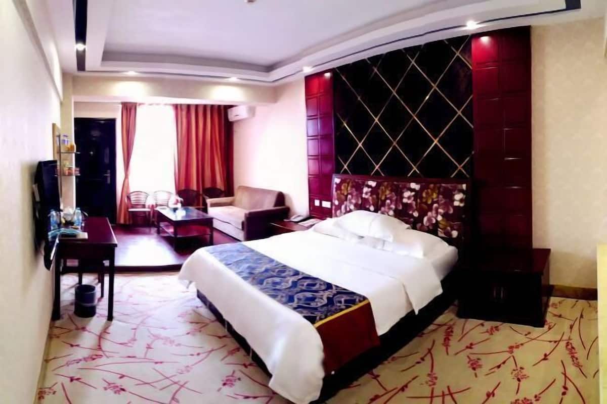 Ein Hotelzimmer mit Bett, Schreibtisch, Stuhl, Fernseher und einem Fenster mit Vorhängen.