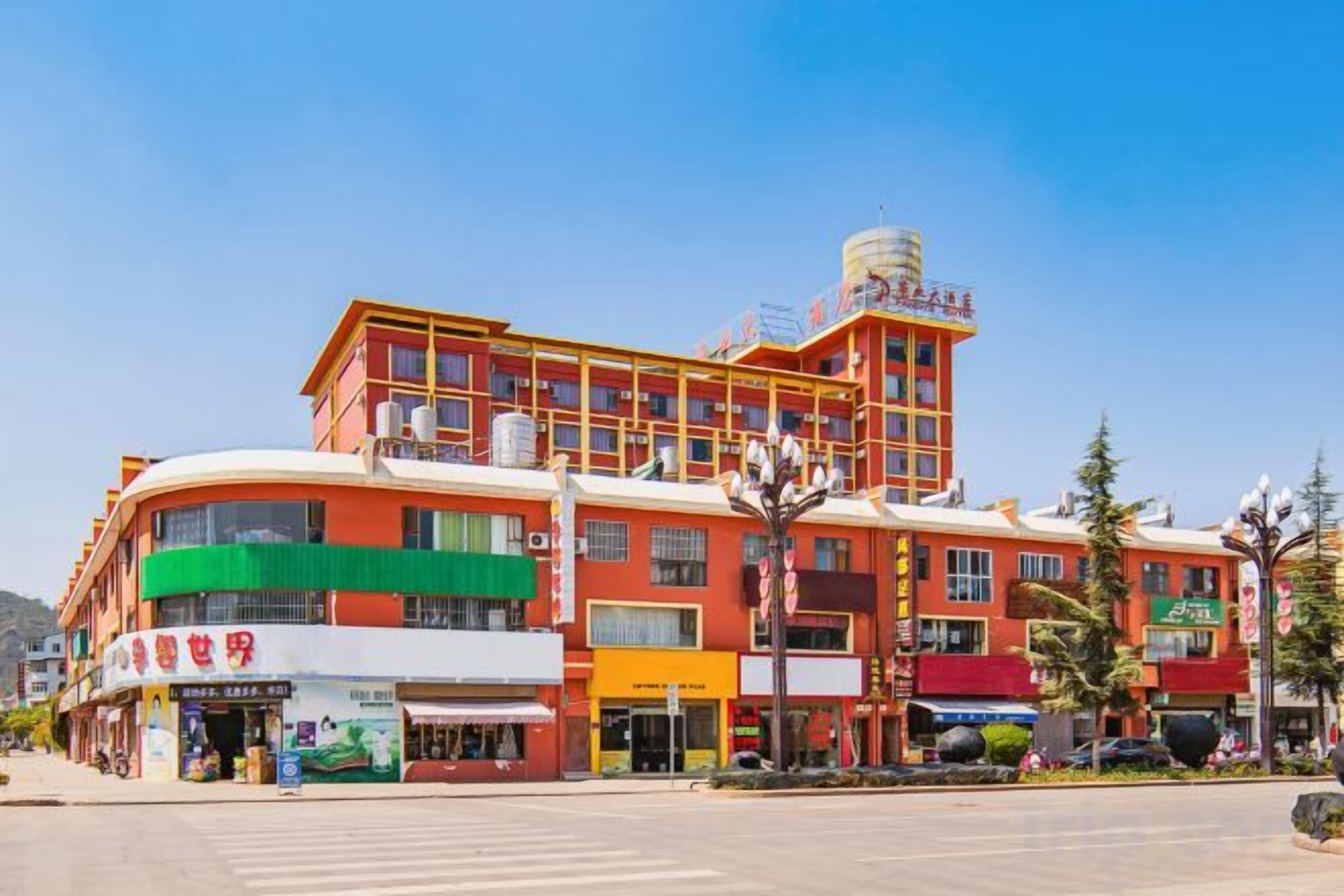A multi-story hotel with a curved facade, multiple ground-level shops, and a clear sky.