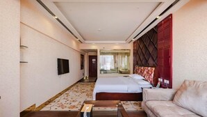 A hotel room with a bed, a sofa, a TV, and a window.