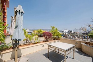 A rooftop terrace with a table and chairs, a covered seating area, and a view of the cityscape. - Pangye Hotel (Dayao)
