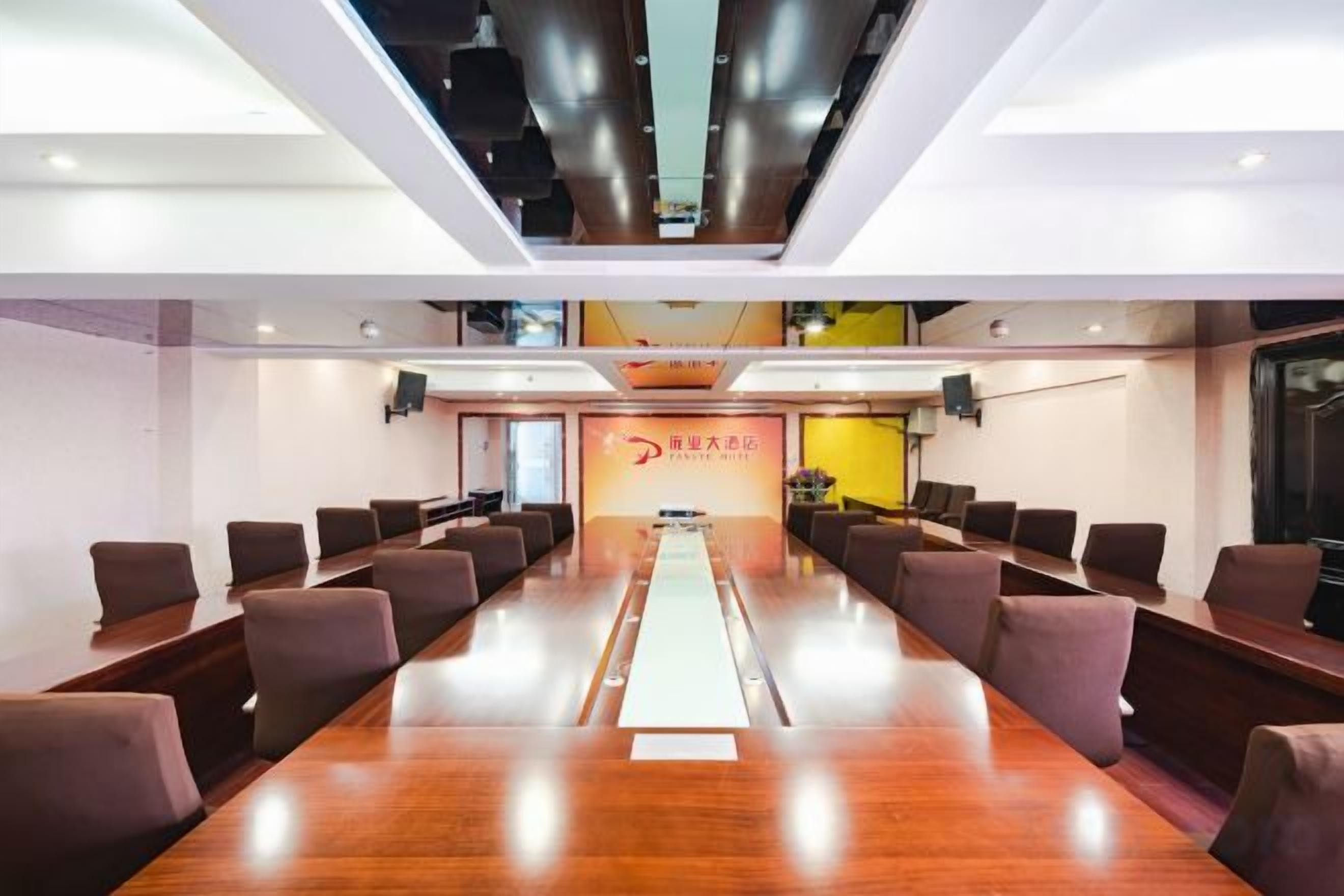 A conference room with a long table, chairs, and a banner with text.