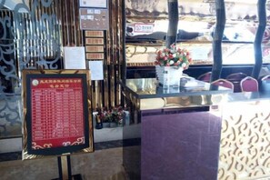 A reception area with a menu board, decorative wall patterns, and a vase with flowers. - Pangye Hotel (Dayao)