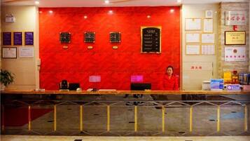 A reception desk with a red wall, framed certificates, and a woman standing behind it.