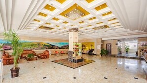 A spacious lobby with a marble floor, a central column, and a chandelier.
