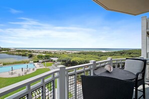 Een balkon met uitzicht op een zwembad, strand en zee.
