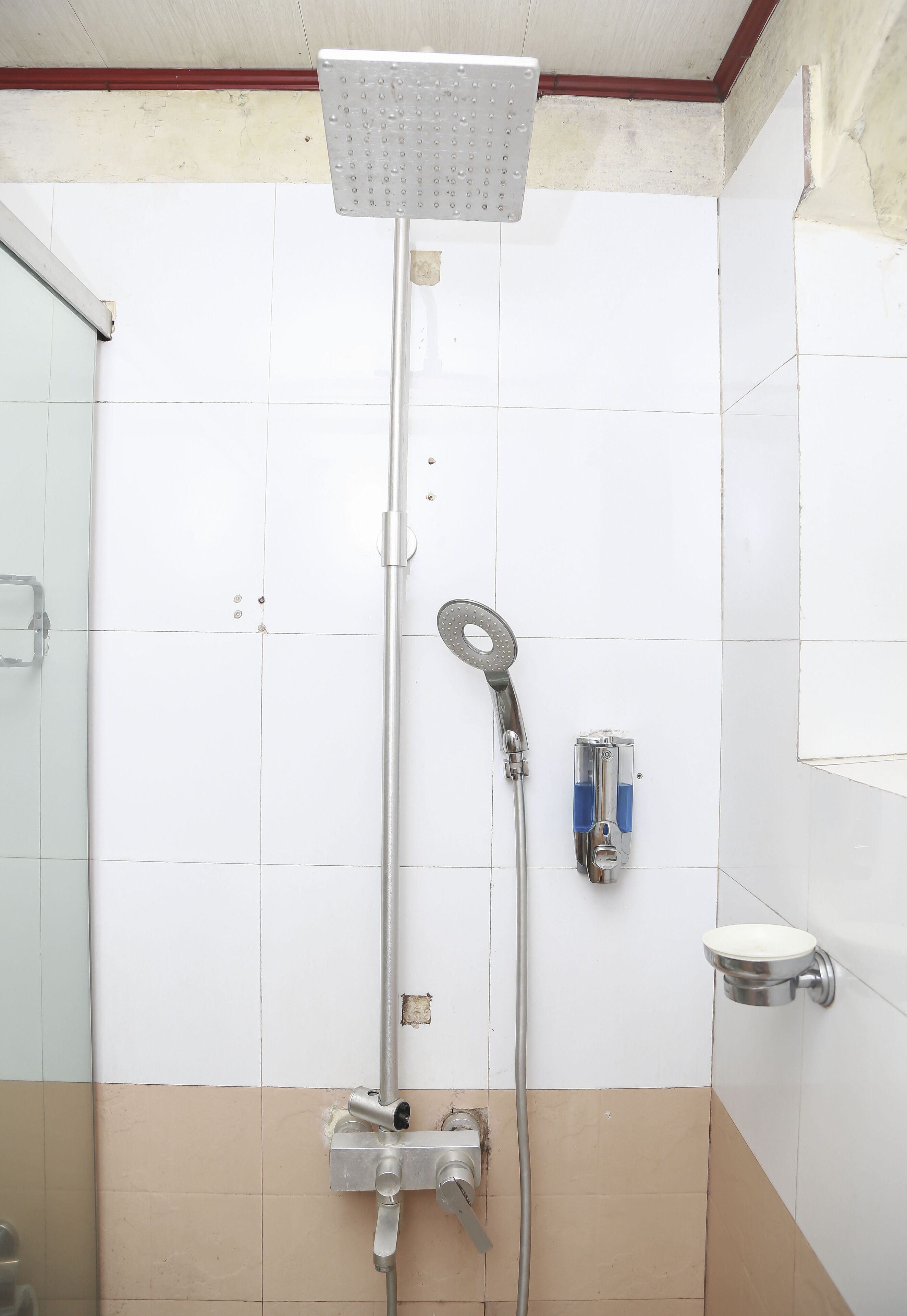 A shower with a handheld showerhead and a wall-mounted faucet.