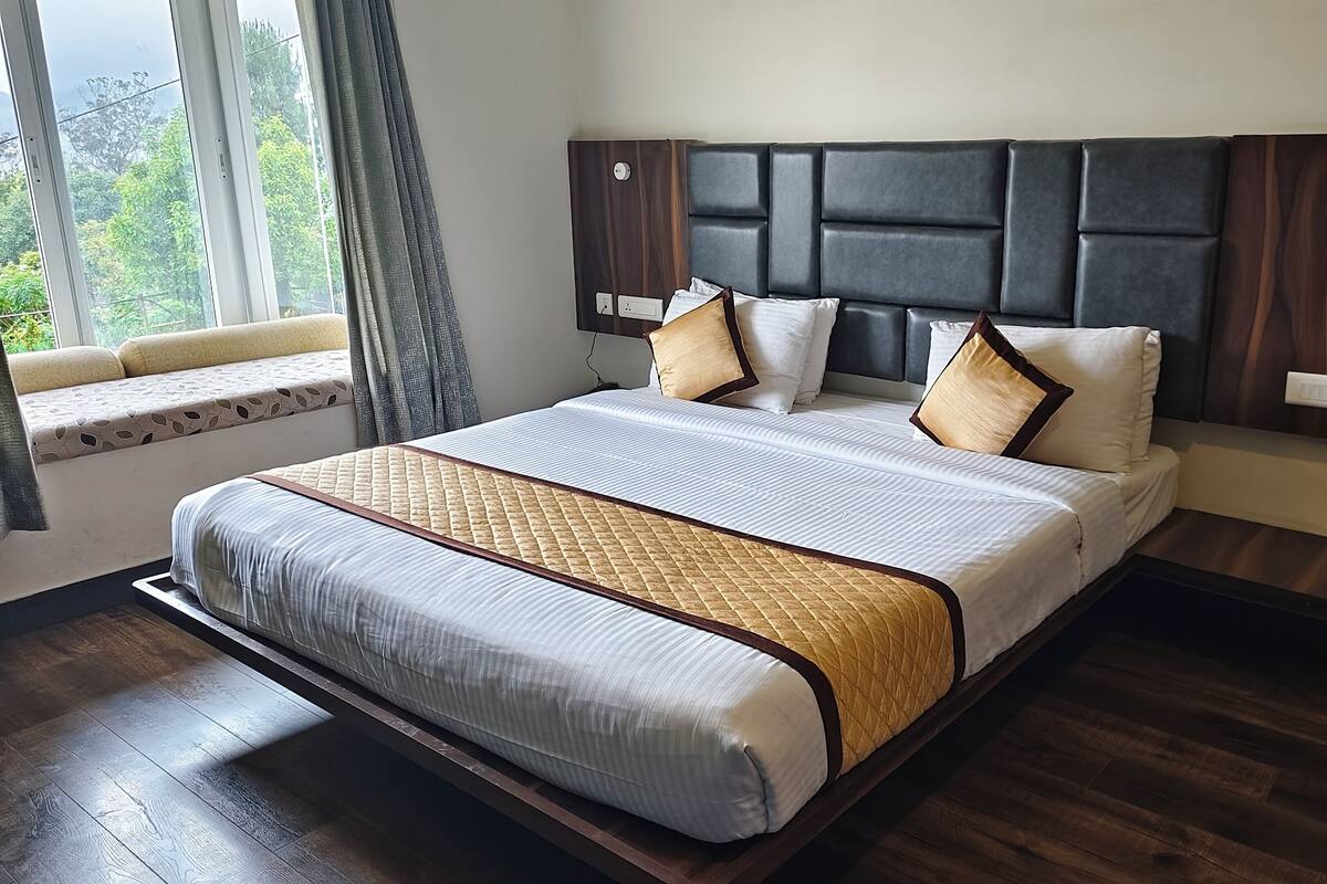 Een moderne slaapkamer met een groot bed, een hoofdvoorkant met opbergruimte, een raam met uitzicht op groen en een houten vloer.