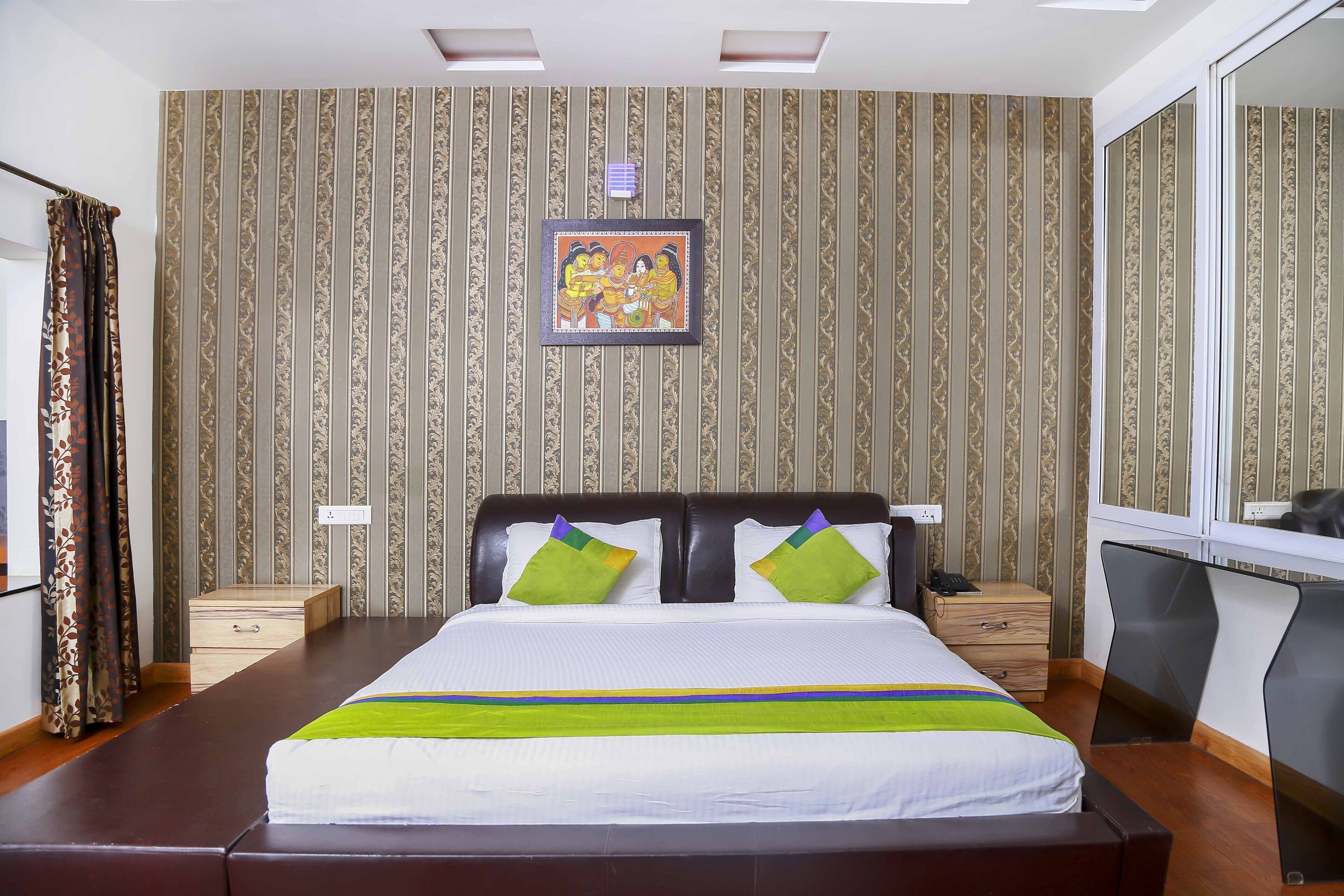 A neatly made bed with a striped headboard, a bedside table with a lamp, and a wall with a framed picture.