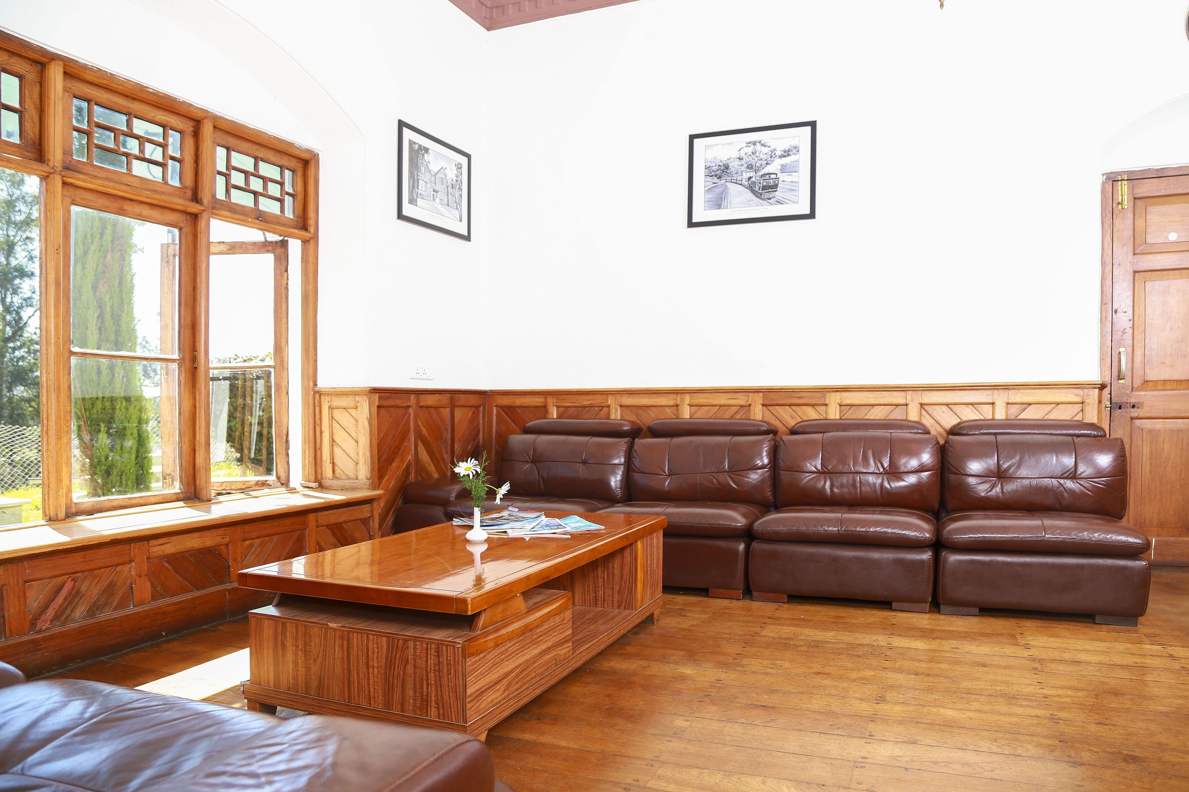A living room with a wooden coffee table, leather sofa, and large windows.