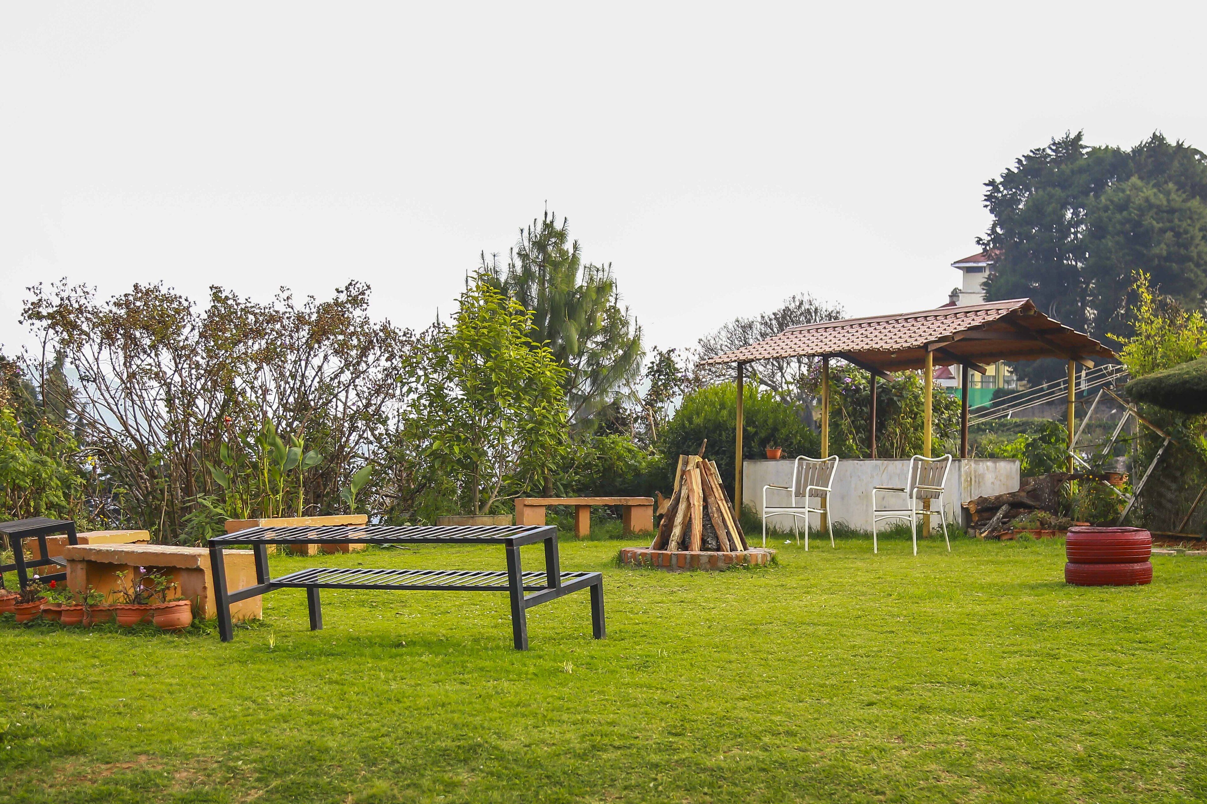 A grassy outdoor area with a wooden bench, a small table, and a gazebo.