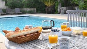 A breakfast setup by a pool with croissants, juice, and coffee. - Villa for 10 • Pool • 5 Suites • Grimaud (Grimaud)