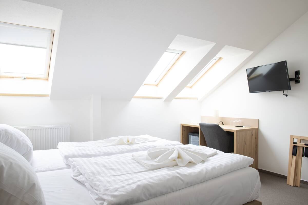 Ein modernes Hotelzimmer mit Bett, Schreibtisch und Fernseher.