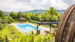 A swimming pool with lounge chairs and a gazebo, surrounded by greenery and hills in the background. - Amenity Penzion Horní Věstonice (Horní Vestonice)