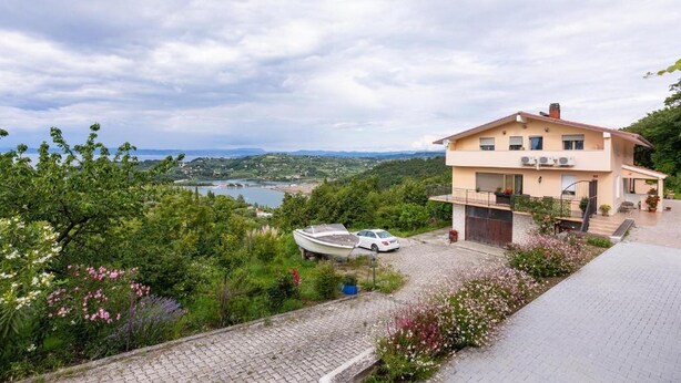 Une maison à deux étages avec vue sur un lac et des collines.