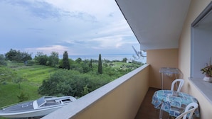 Un balcon donnant sur un bateau, une table avec des chaises et une plante en pot.