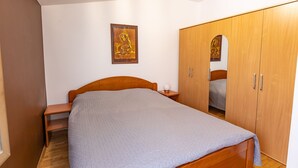 Une chambre à coucher avec un lit en bois, une table de chevet, une armoire et un tableau encadré au mur.