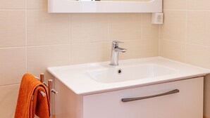 Une salle de bain avec un lavabo blanc, un miroir et un porte-serviettes.