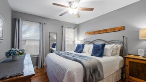 A bedroom with a bed, bedside tables, a ceiling fan, and a window with blinds.