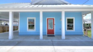 A single-story house with a red door, blue siding, and a covered porch.