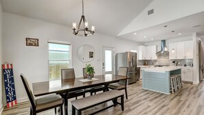 A modern kitchen with a central island, stainless steel appliances, and a dining area with a bench.