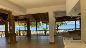 A covered outdoor area with wooden pillars, a tiled floor, and a view of the sea. - Family Comfort In Jamaica - Enjoy 7 Miles Of White Sand Beach! Villa by RedAwning (Negril)