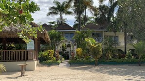 A hotel entrance with a thatched structure, a signboard, and a pathway leading to the main building. - Family Comfort In Jamaica - Enjoy 7 Miles Of White Sand Beach! Villa by RedAwning (Negril)