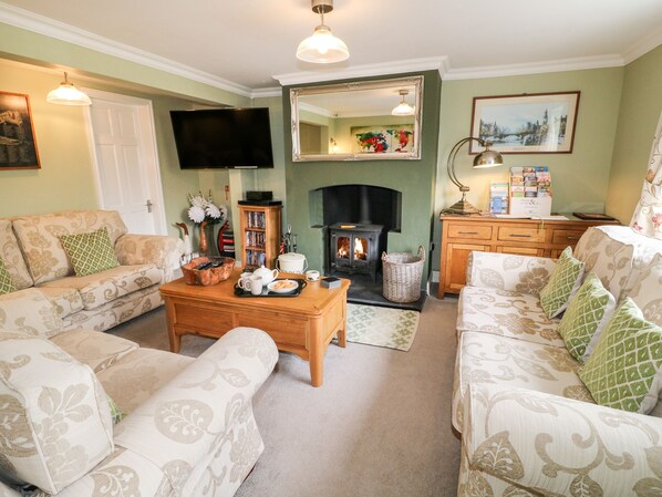 A cozy living room with a fireplace, sofas, a coffee table, and a television.