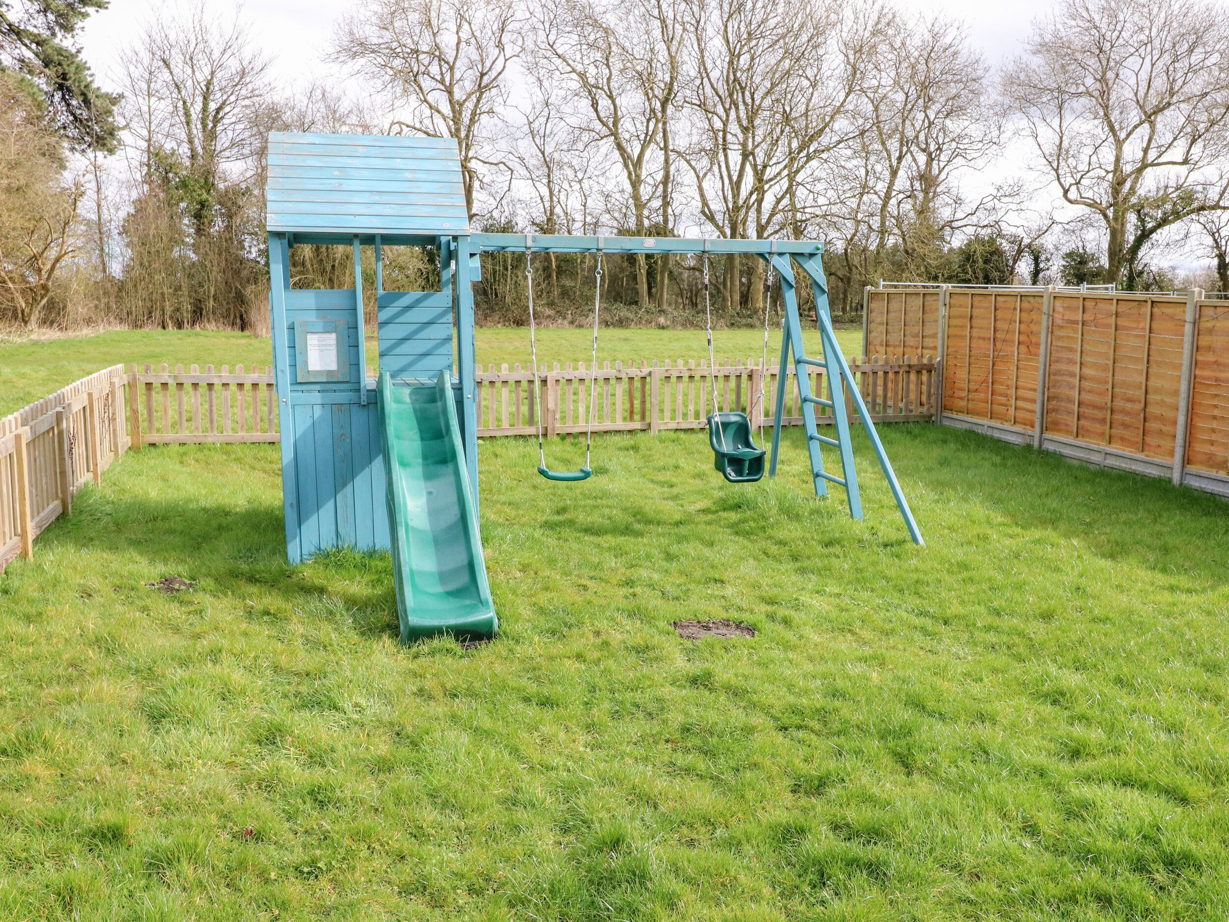 A playground with a slide, swings, and a swing set.