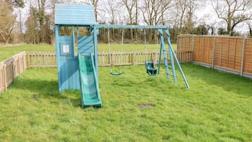 A playground with a slide, swings, and a swing set.