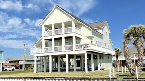 A two-story house with a balcony on the first floor and a covered porch.