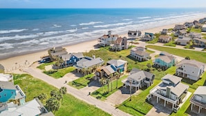 Zona residencial costeira com casas, uma praia e um céu azul límpido.