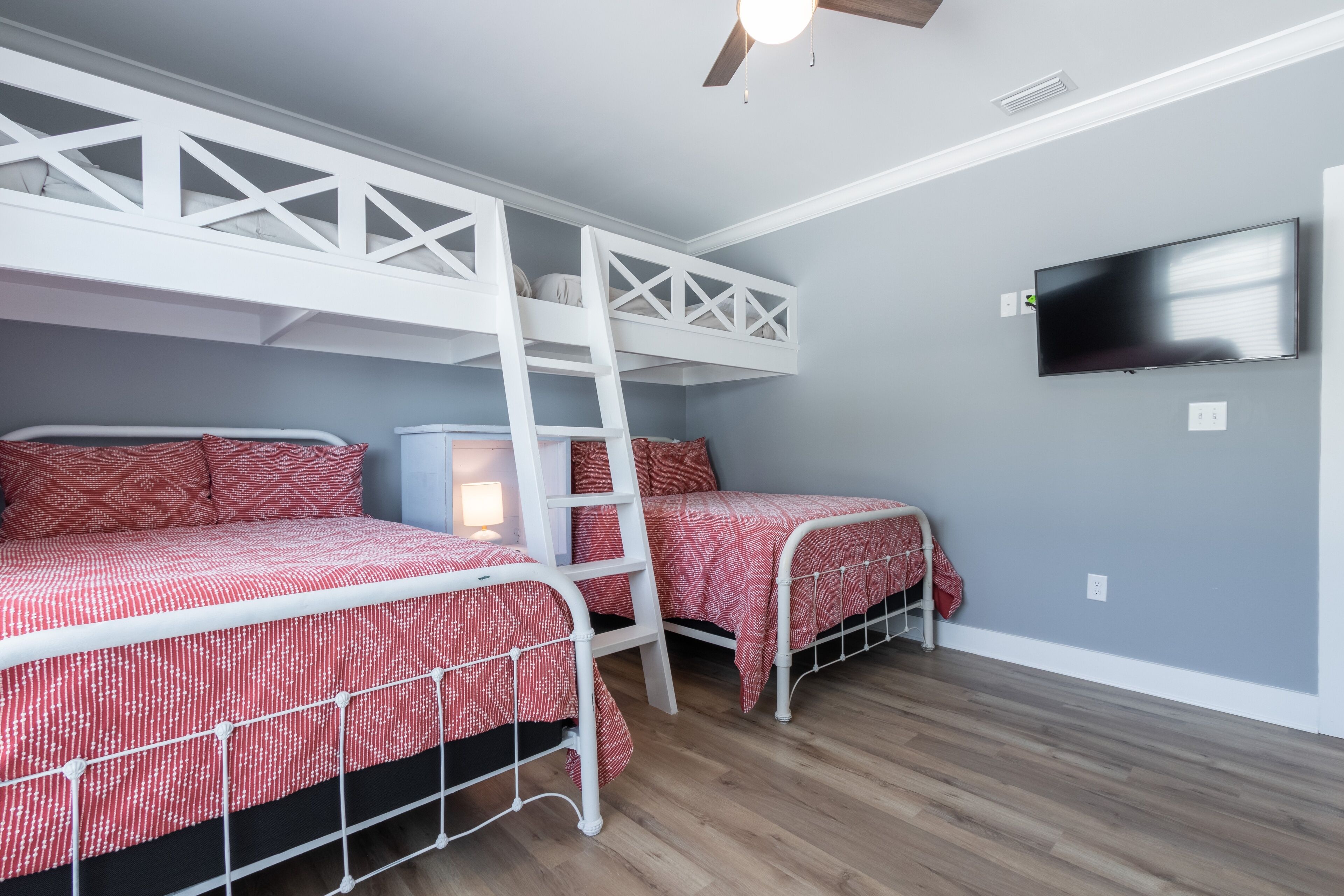 A bedroom with bunk beds, a TV, and a ceiling fan.