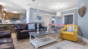 A modern living room with a dark brown leather sofa, a yellow armchair, and a wooden coffee table. - The Rookery Iii 7011 3 Bedroom Cottage by RedAwning (Gulf Shores)