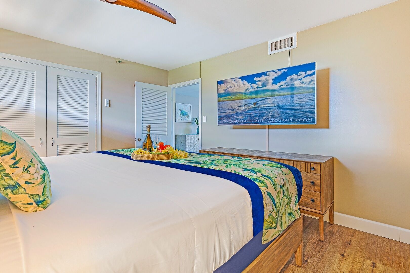 A bedroom with a bed, a wooden nightstand, a painting, and a window with blinds.