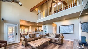 A spacious living room with a large sectional sofa, a wooden coffee table, and a dining area in the background.