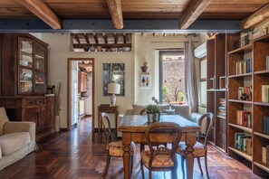 A cozy dining area with wooden furniture, a bookshelf, and a view of the outside.