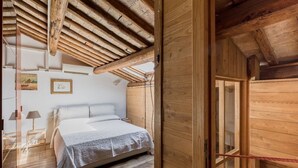 Una habitación de madera con cama, mesita de noche y ventana.