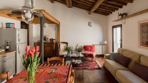 Una sala de estar acogedora con techo de madera, un comedor con mesa lista para dos comensales y un sofá.