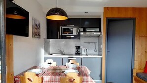 Una cucina compatta con elettrodomestici moderni, un tavolo da pranzo con tovaglia a quadri e sedie in legno.