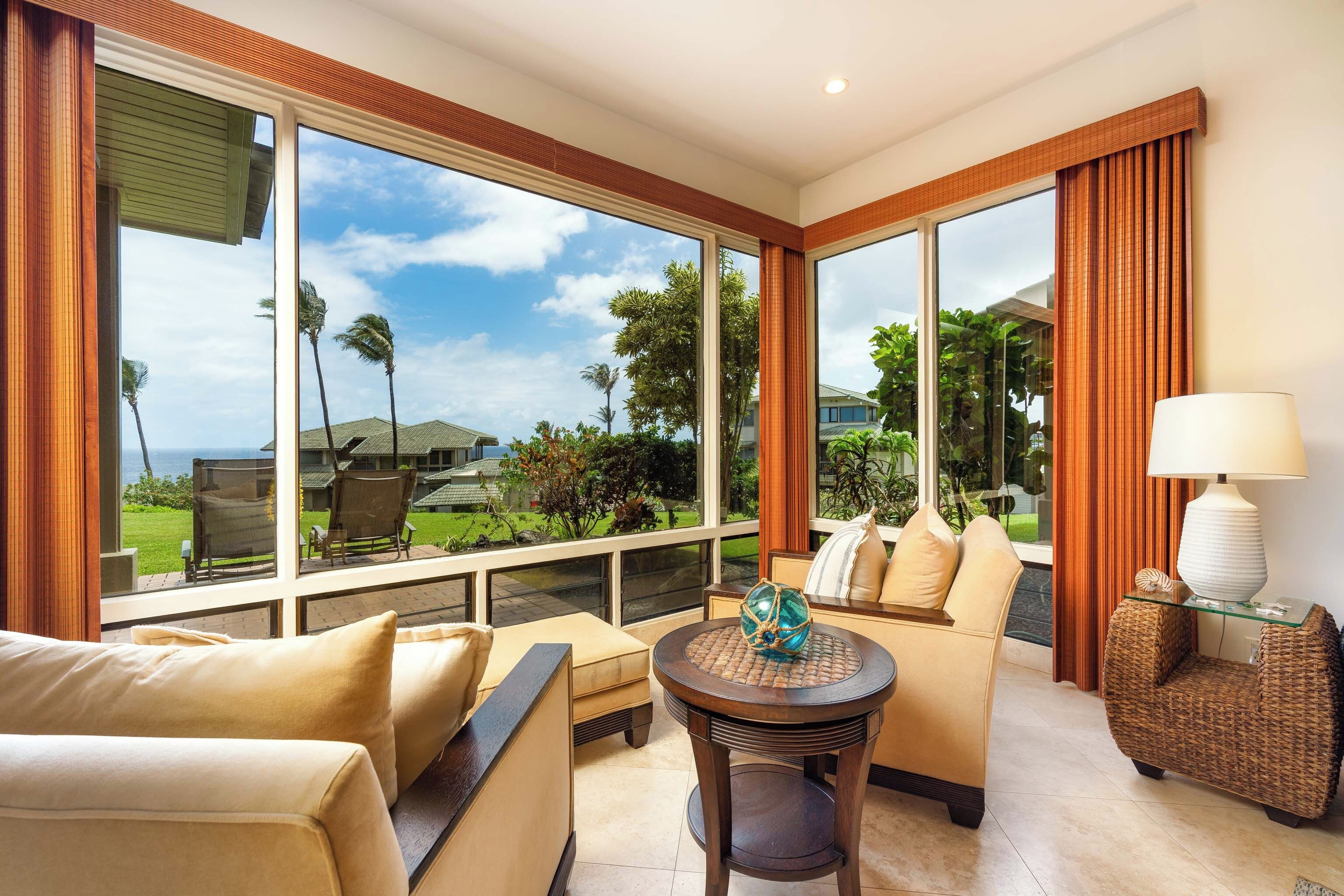 A spacious room with large windows, a round table, and a comfortable seating area.