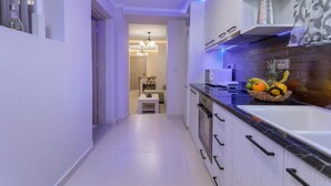 A modern kitchen with white cabinets, a black countertop, and a fruit basket. - Evia's Apartment   New Apartment In Town! (Zakynthos)