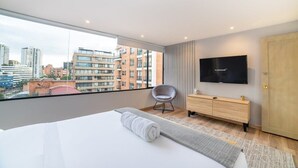 Une chambre d’hôtel moderne avec un grand lit, une télévision, une armoire en bois et une vue sur la ville.