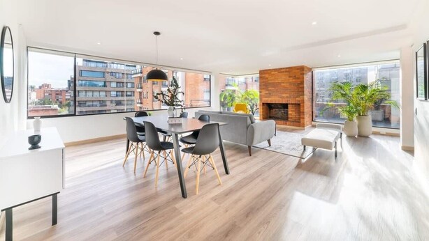 Un salon moderne comprenant un coin repas, une cheminée et de grandes fenêtres offrant une vue sur la ville.